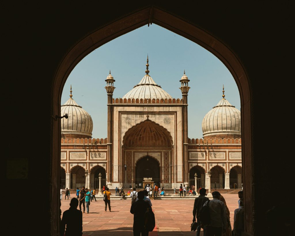 A captivating view through arches of the iconic Jama Masjid in New Delhi, bustling with visitors.