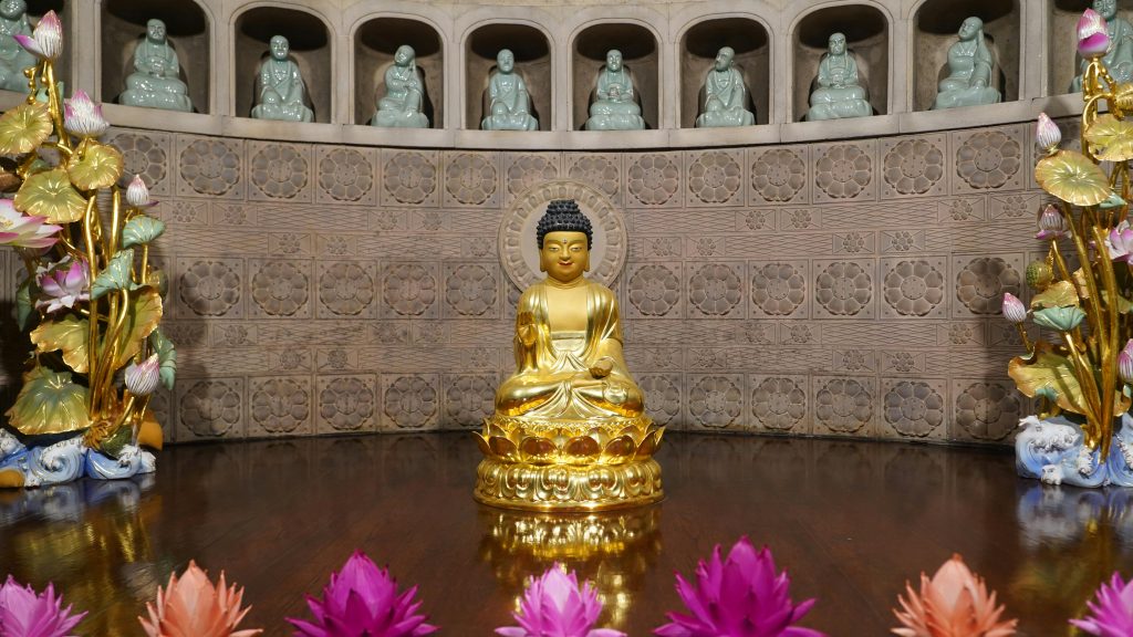 A serene golden Buddha statue inside a temple in Seoul, Korea, adorned with lotus flowers.